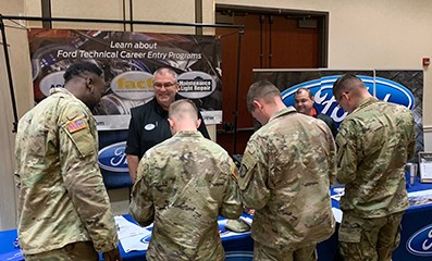 Four male veterans standing at a Ford career fair booth